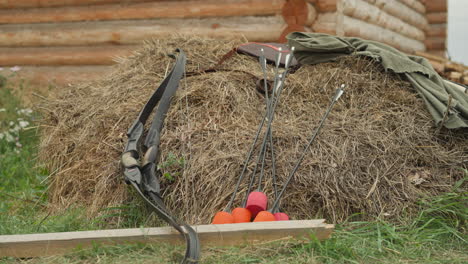 bow and arrow tipped for ignition lie near pile of straw