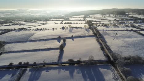 Frío-Invierno-Nevado-Británico-Mosaico-Tierras-De-Cultivo-Campo-Rural-Escena-Aérea-Al-Amanecer-Lento-Descender-Hacia-Adelante