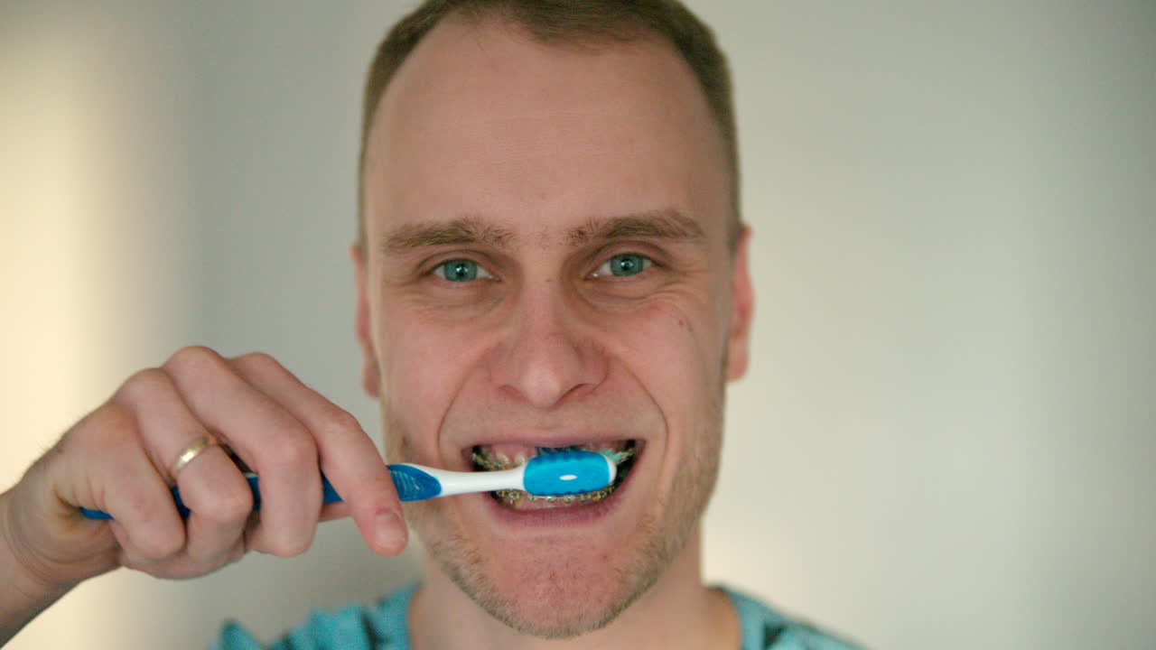 Close up of young man happily put his toothbrush to his mouth and starts brushing