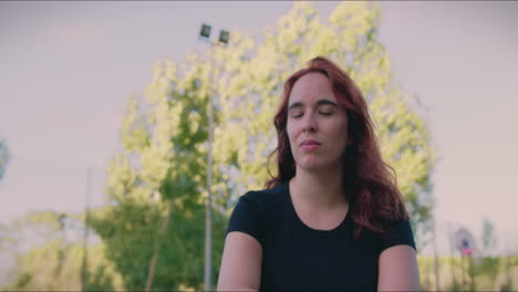 la chica pelirroja de la cancha de baloncesto sentada en una pelota mira a la cámara y sonríe