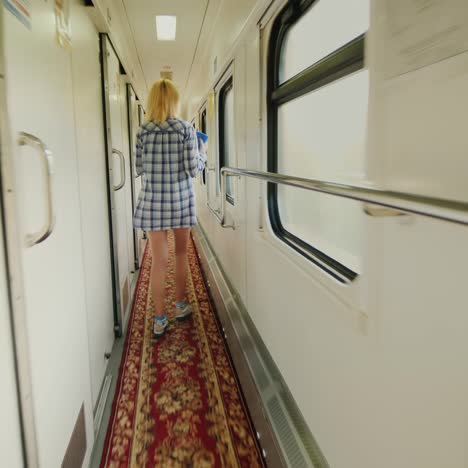 a woman with a towel is walking along the carriage of a passenger train