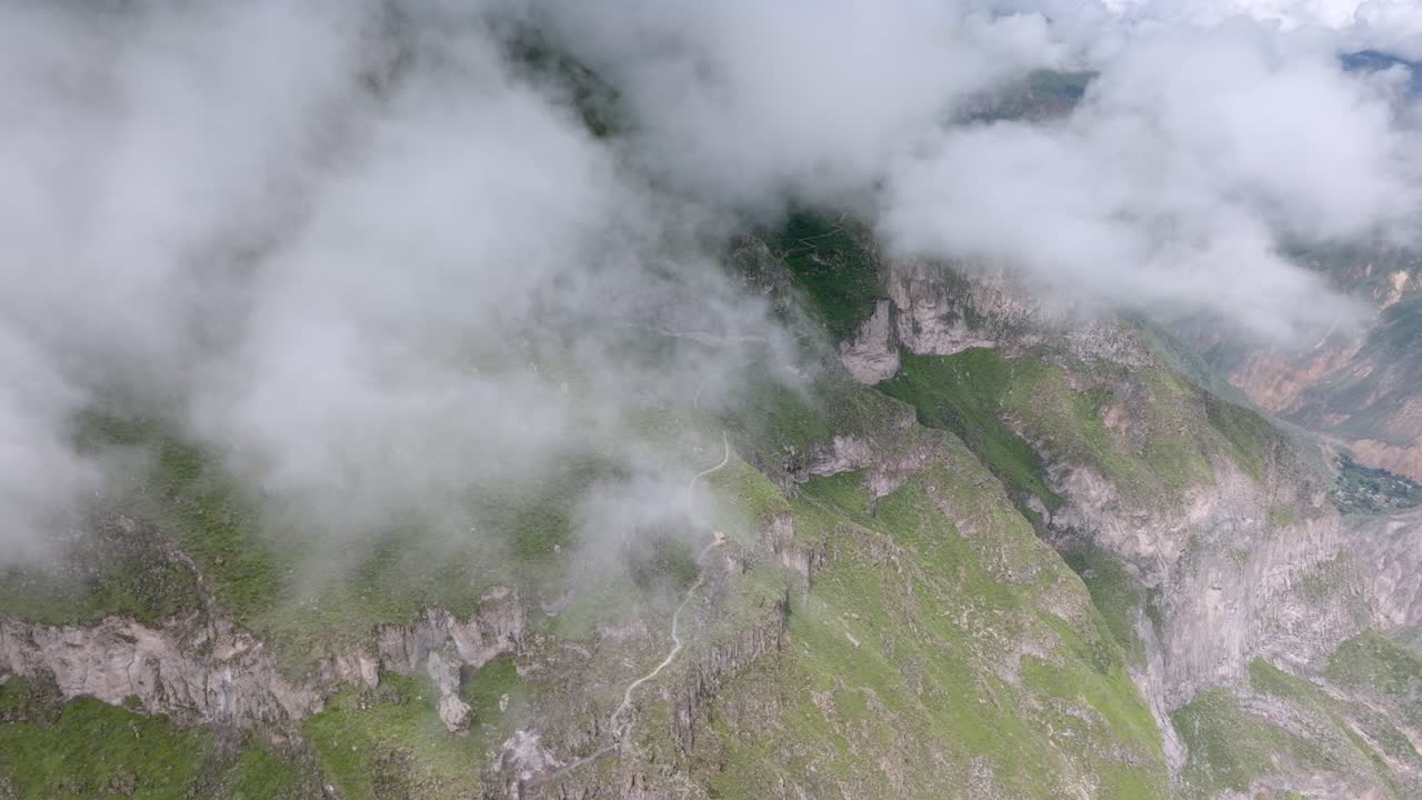 A stunning aerial view of a trekking trail winding through the Peruvian highlands. The drone glides above the clouds, revealing a mystical landscape perfect for adventure and nature content.