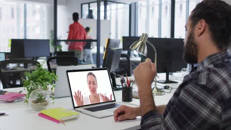 Middle-eastern-man-having-a-video-call-with-female-colleague-on-laptop-at-office