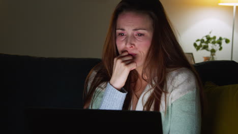 Close-Up-Of-Anxious-Woman-Sitting-On-Sofa-At-Home-At-Night-Looking-At-Laptop-Concerned-About-Social-Media-Or-Bad-News-8