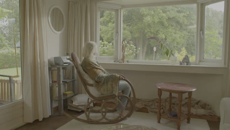 old woman sitting in a rocking chair covered with a blanket in a cozy living room