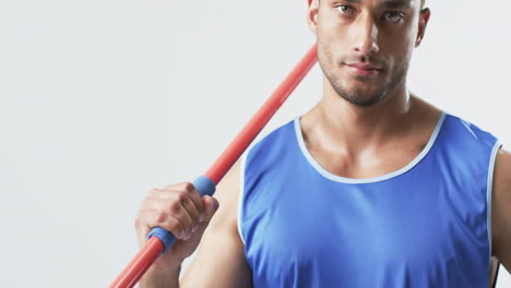 young biracial athlete man holds a javelin on a white background