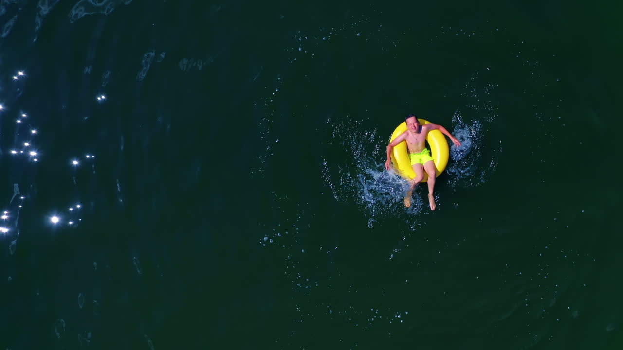 Boy swimming on pool ring. Top down view of boy floating on swim ring