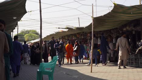 dynamic islamabad market atmosphere with people interacting and purchasing groceries from a variety of street vendors and stalls amidst a kaleidoscope of colors and sounds.