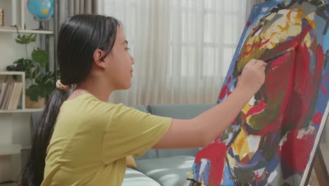 vista lateral de un artista asiático con un pincel de colores mixtos y pintando la oreja de una chica en el lienzo
