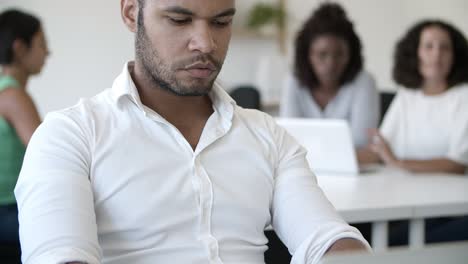 una foto de cerca de un programador cansado trabajando en una oficina de espacio abierto.