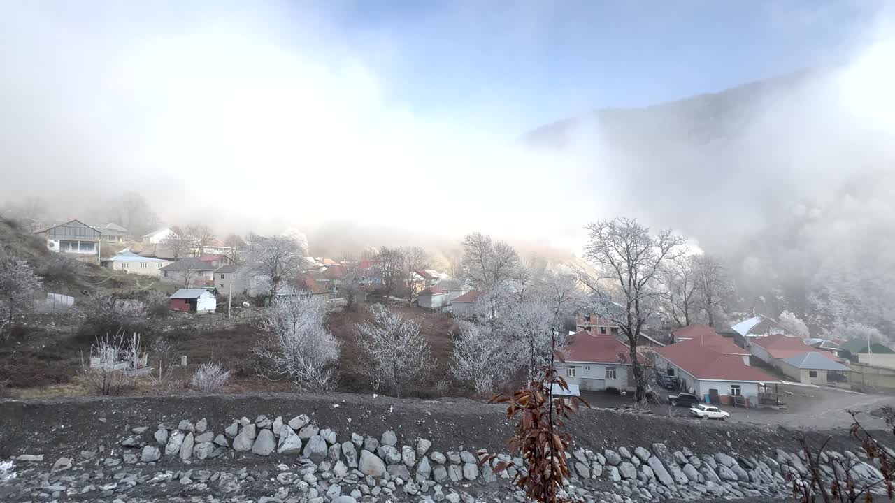 Snow-dusted village homes and trees in misty mountain air of Gabala. Gabala, Azerbaijan
