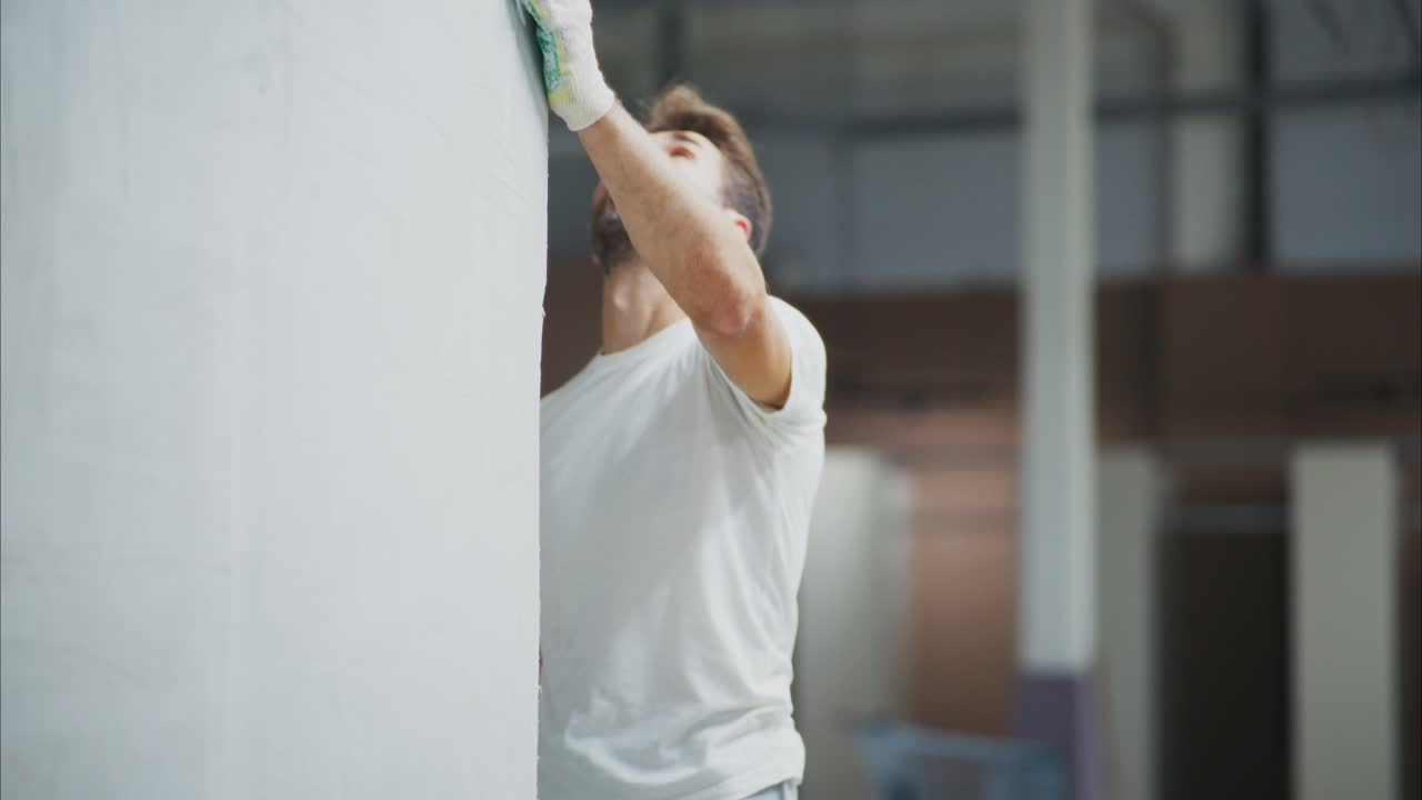 A Focused Painter Working on a Wall: Capturing the Determination and Precision of Craftsmanship in an Indoor Renovation Project