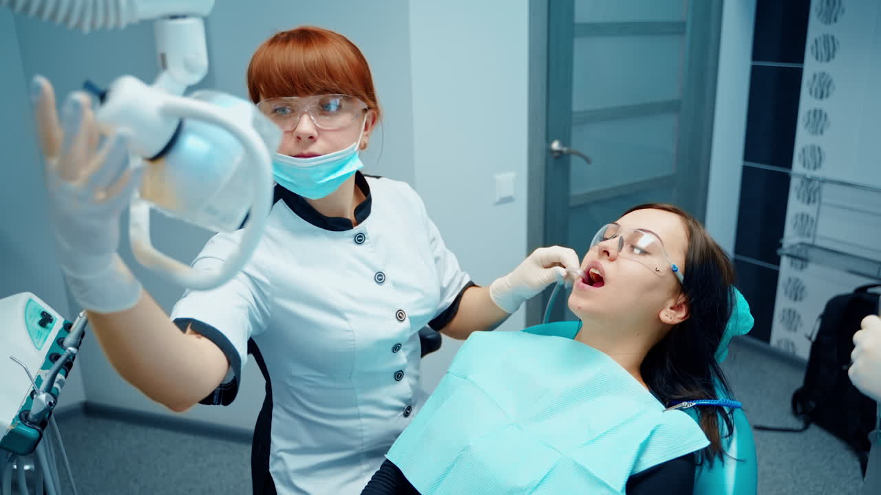 Woman in stomatology clinic. Stomatology doctor treating woman teeth in dentistry clinic