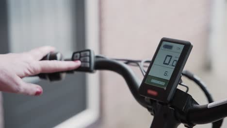 Close-up-of-a-woman's-hand-as-she-adjusts-the-acceleration-power-of-a-electric-bicycle-from-the-buttons-on-the-handlebars