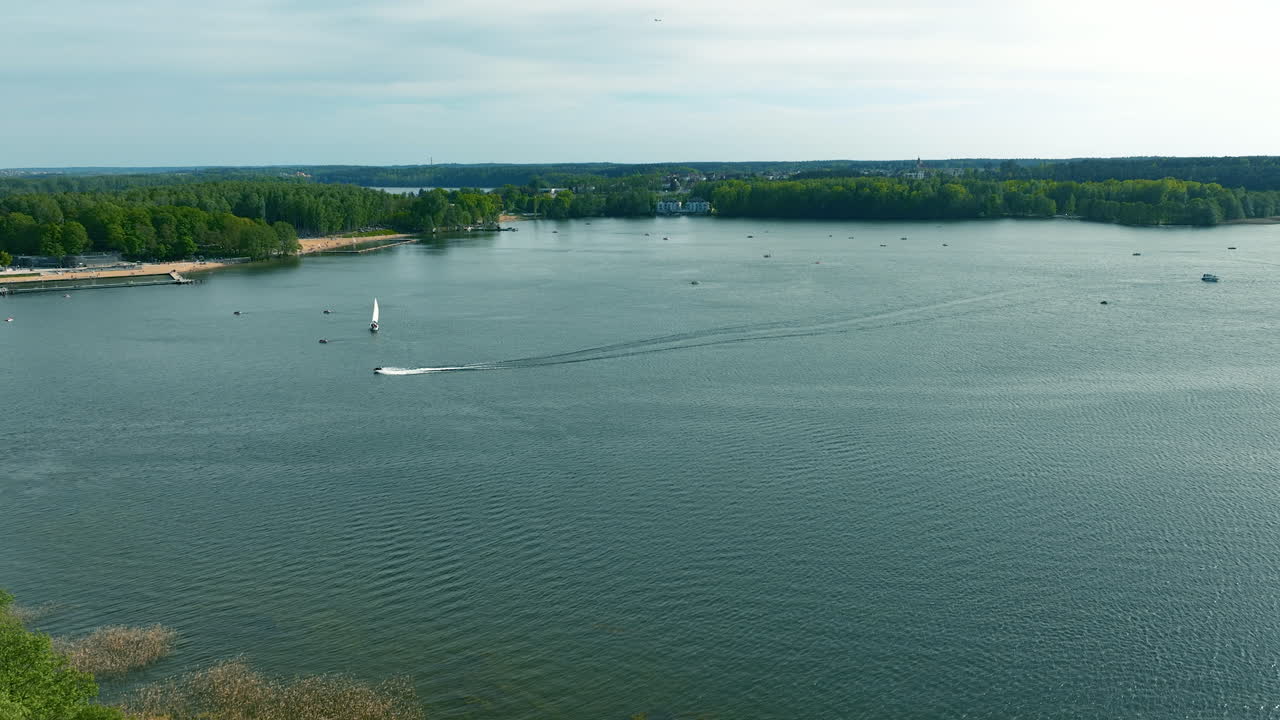una toma aérea más amplia captura el lago ukiel en medio de un vasto paisaje, destacando la interacción entre el entorno natural y los entornos urbanos cercanos.