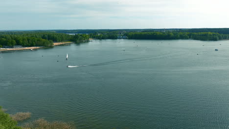 A-broader-aerial-shot-captures-Ukiel-Lake-amidst-a-vast-landscape,-highlighting-the-interplay-between-the-natural-environment-and-nearby-urban-settings