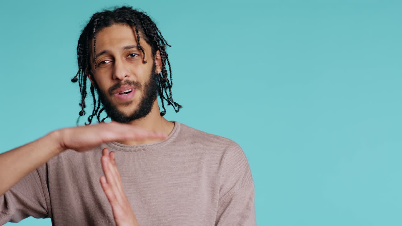Assertive man asking for timeout, doing hand gestures, studio background