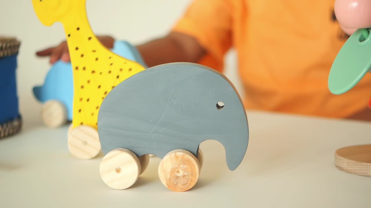 Child Playing with Wooden Elephant and Giraffe Toys