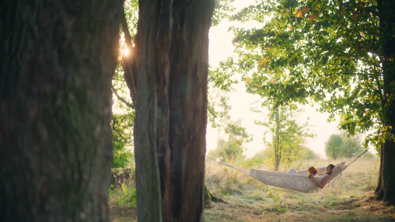 Girl daydreams in hammock during sunset glow