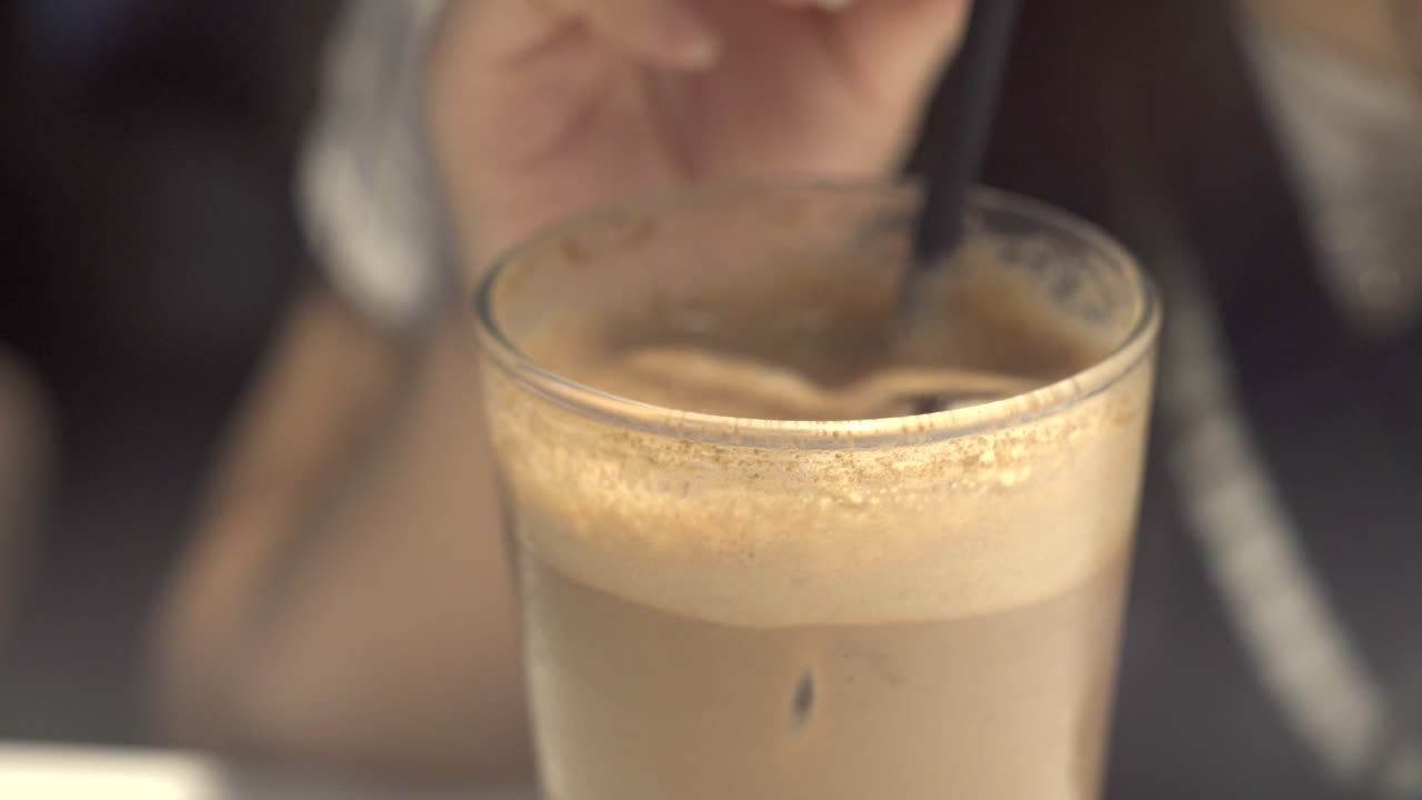 Close up shot of a girl sipping on iced coffee