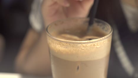 close up shot of a girl sipping on iced coffee