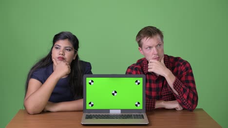 joven pareja de negocios multiétnica juntos contra un fondo verde