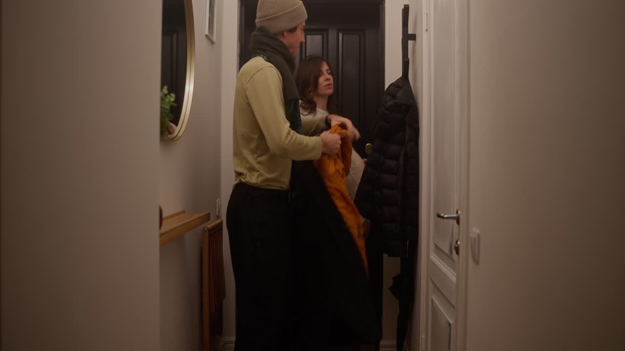 Couple putting away coats in hallway