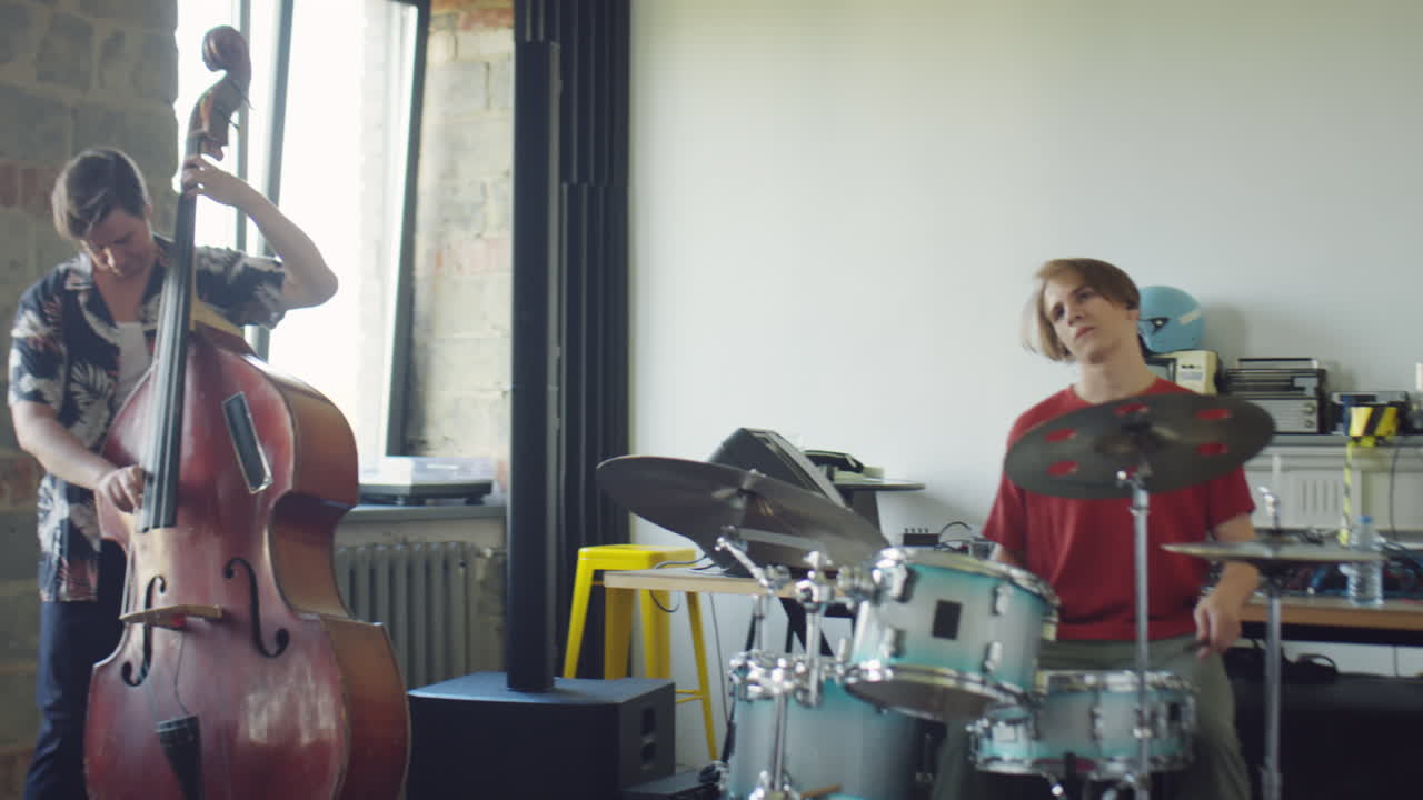 A musical duo rehearsing with a drummer and an upright bassist