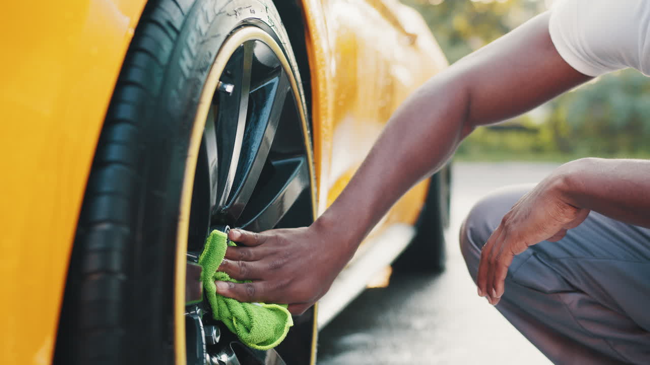 hombre lavando un coche amarillo
