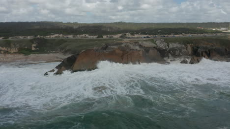aerial dolly of a wild sea slamming into cliffs at shoreline