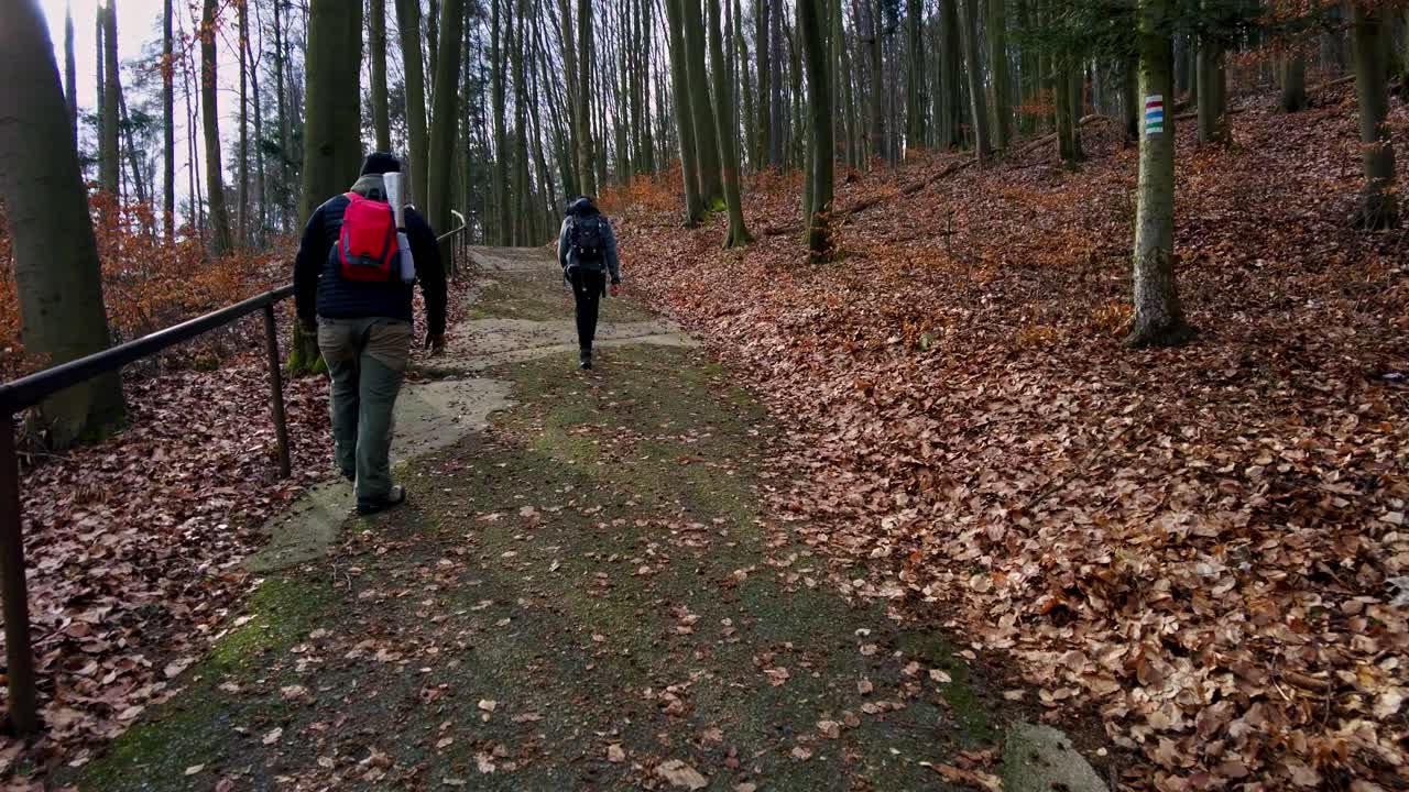 Two men walking together in slow motion along a path up a hill
