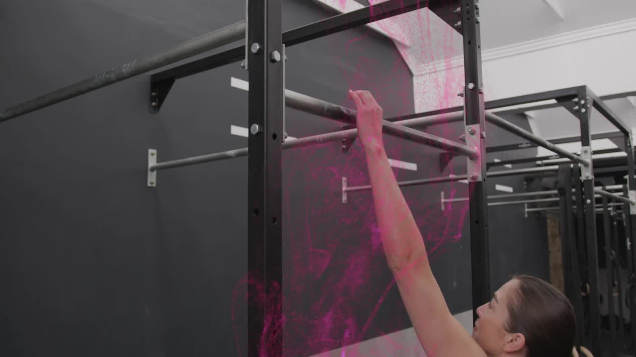 Woman entering gym with pink smoke appearing, reaching, grasping bar, adjusting grip for fitness