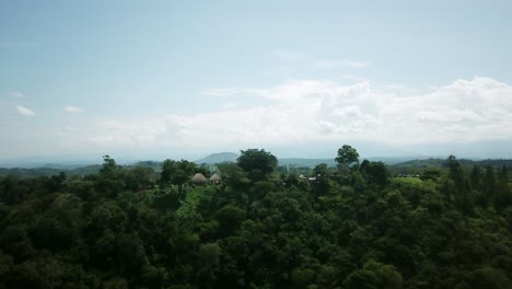 Bewachsene-Hügel-Und-Strohgedeckte-Lodges-In-Uganda-Afrika-Mit-Kratersee-Im-Hintergrund