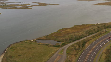 dolly-shot-forward-of-a-drone-camera-on-a-cloudy-day,-then-the-camera-tilts-down-to-view-marshland-shoreline---vegetation