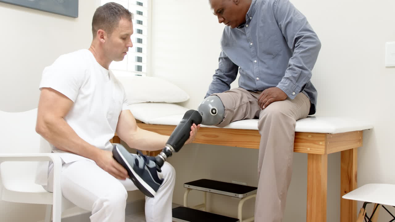 Technician adjusting prosthetic leg for patient sitting on examination table