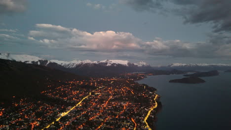 bariloche, argentina luces de la ciudad brillan con montañas y lagos, panorámica aérea que establece el seguimiento a la izquierda
