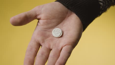 Close-Up-Of-Hand-Holding-Heart-Candy-With-First-Love-Message-On-Yellow-Background-1