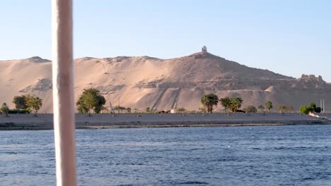 view of a hill next ot the nile river from a boat in upper egypt, aswan