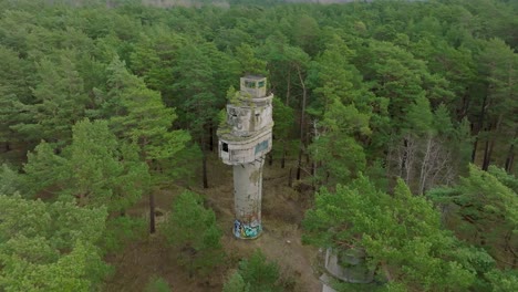 establishing aerial view of old soviet military concrete observation watchtower, pine tree forest, liepaja , military heritage, nordic woodland, wide drone shot moving forward, tilt down