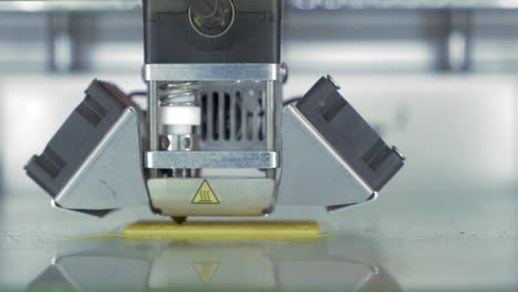 vista de cerca de la impresora 3d en proceso hace piezas para equipos con plástico amarillo