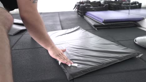 young man at the gym sanitising exercising mat after workout session