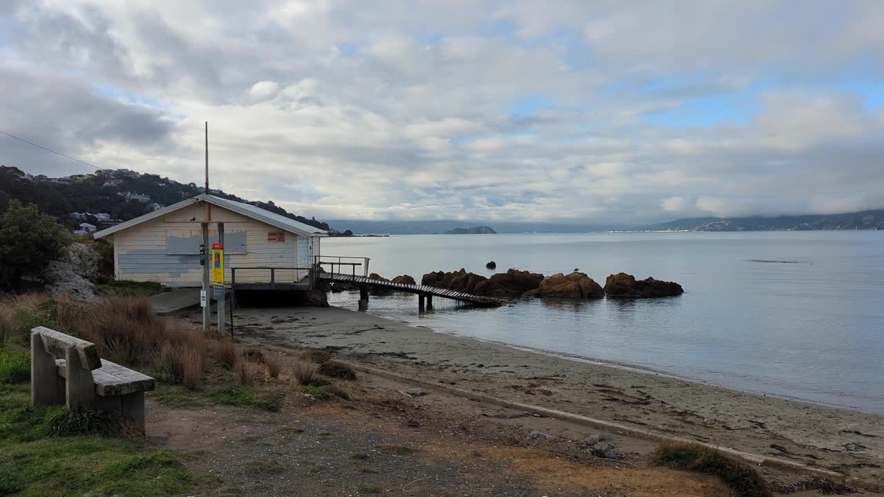 Beach scene with building, sea, and cloudy sky