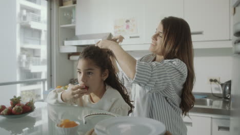 careful mom doing ponytail for daughter at home