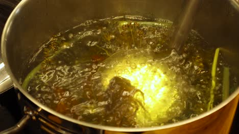 Close up top down view of alive crayfish crab or lobsters being put into boiling hot dill water in a steel pot at a kitchen indoors to boil and cook. The Crayfish turn red while cooking in hot water