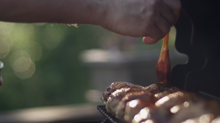 Dad brushes plenty of bbq sauce on the grilled chicken