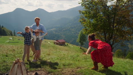 family playing outdoor game together on mountains. parents having fun with kids.