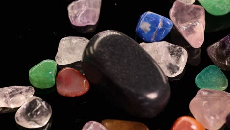 Various chakra stones, including tiger's eye and amethyst, arranged on a black background, showcasing vibrant colors and textures