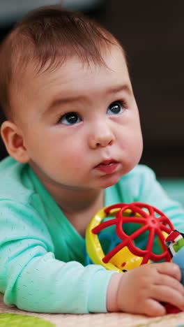 adorable toddler being busy looking at his toys. lovely baby boy looking up and then turning to his toys again. blurred backdrop. vertical video