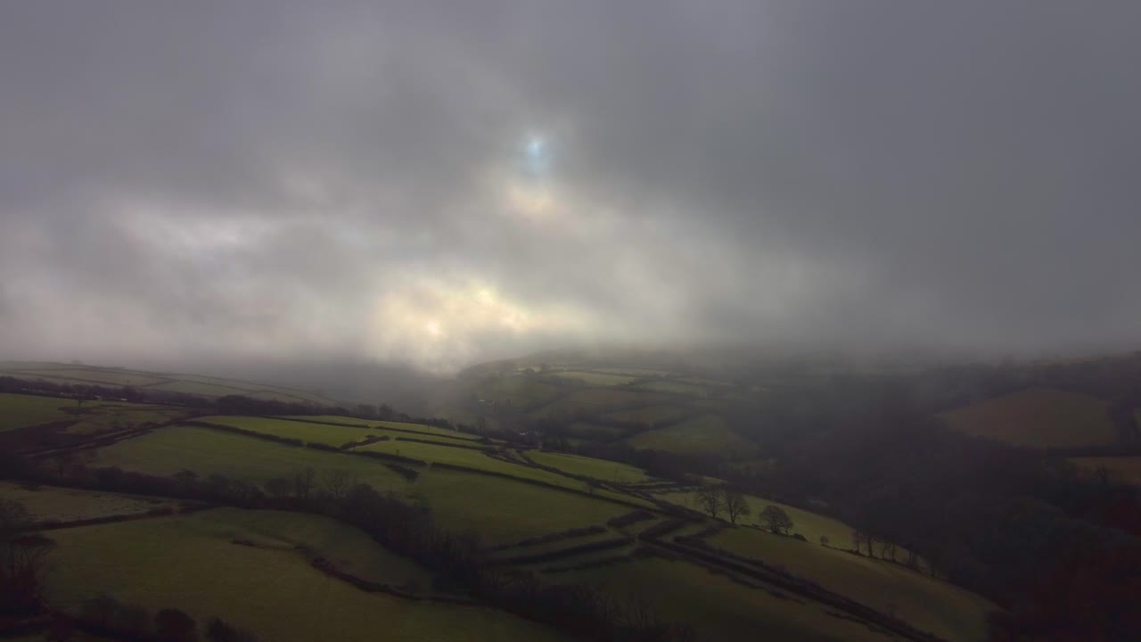 Contrasting Ominous Clouds Over Rural Farmland in Britain with Sectioned Farmed Fields Below. Pushing Aerial Drone Footage of Natural Landscape 4K.
