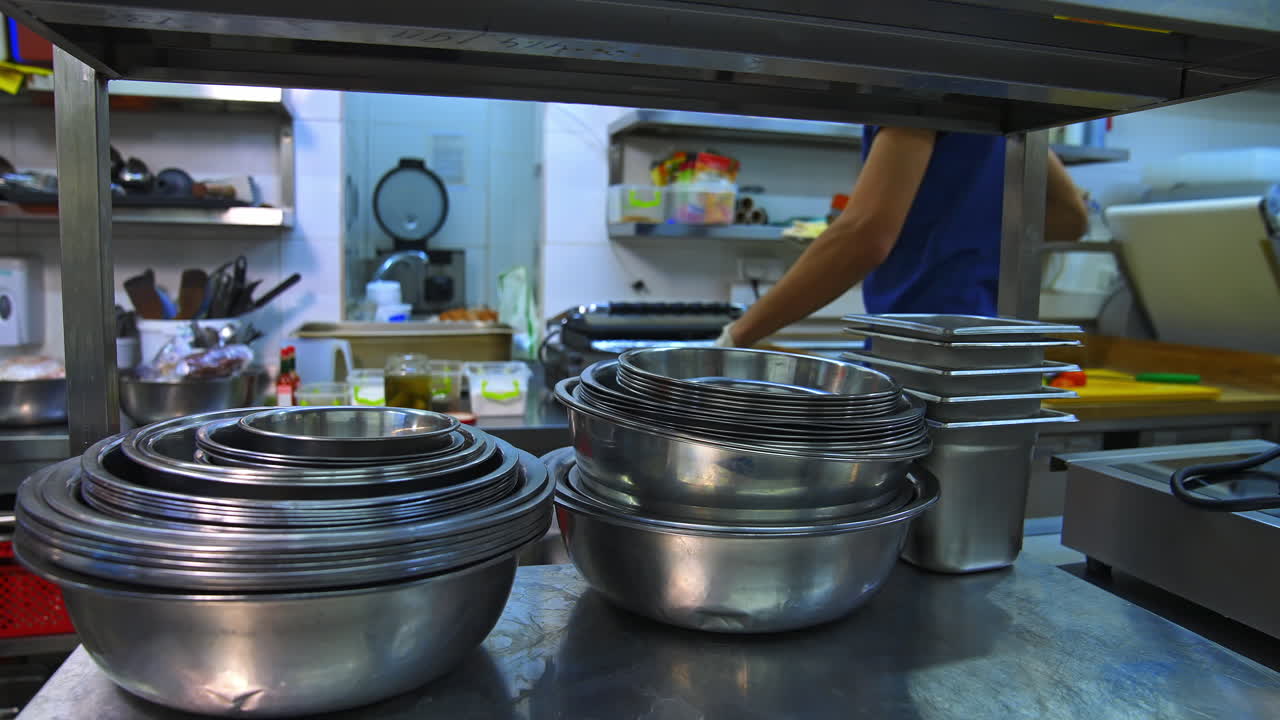 Stainless steel bowl for cooking. Kitchen utensils. Many bowls on shelf in kitchen.